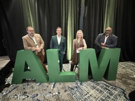 Councilmember Moody, Mayor Gates, Councilmember Smith, Councilmember Moore standing behind large A L M letters