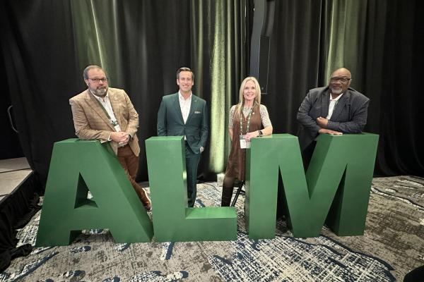 Councilmember Moody, Mayor Gates, Councilmember Smith, Councilmember Moore standing behind large A L M letters